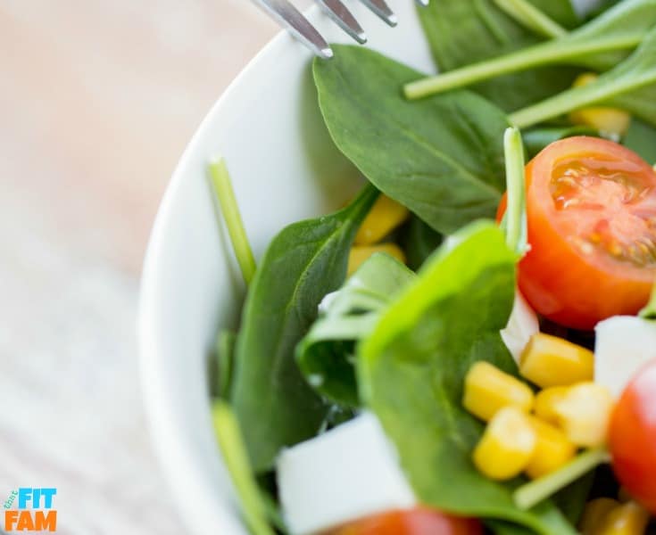 piccola ciotola di insalata fatta con spinaci, pomodori, mais e altre verdure.