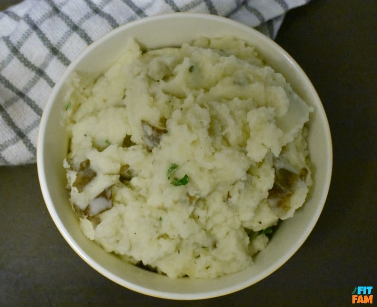 Healthy herb mashed potatoes with mashed cauliflower mixed in. Your kids won't even know they're eating extra veggies! Such a yummy dinner side!