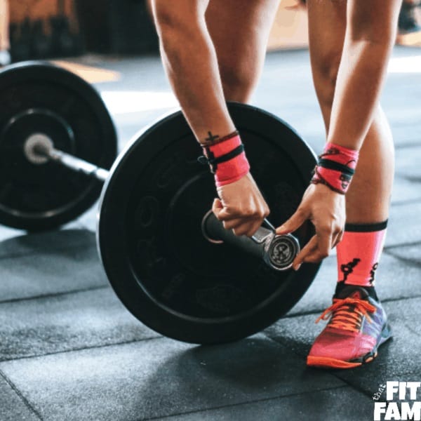 woman loading up barbell for weightlifting routine