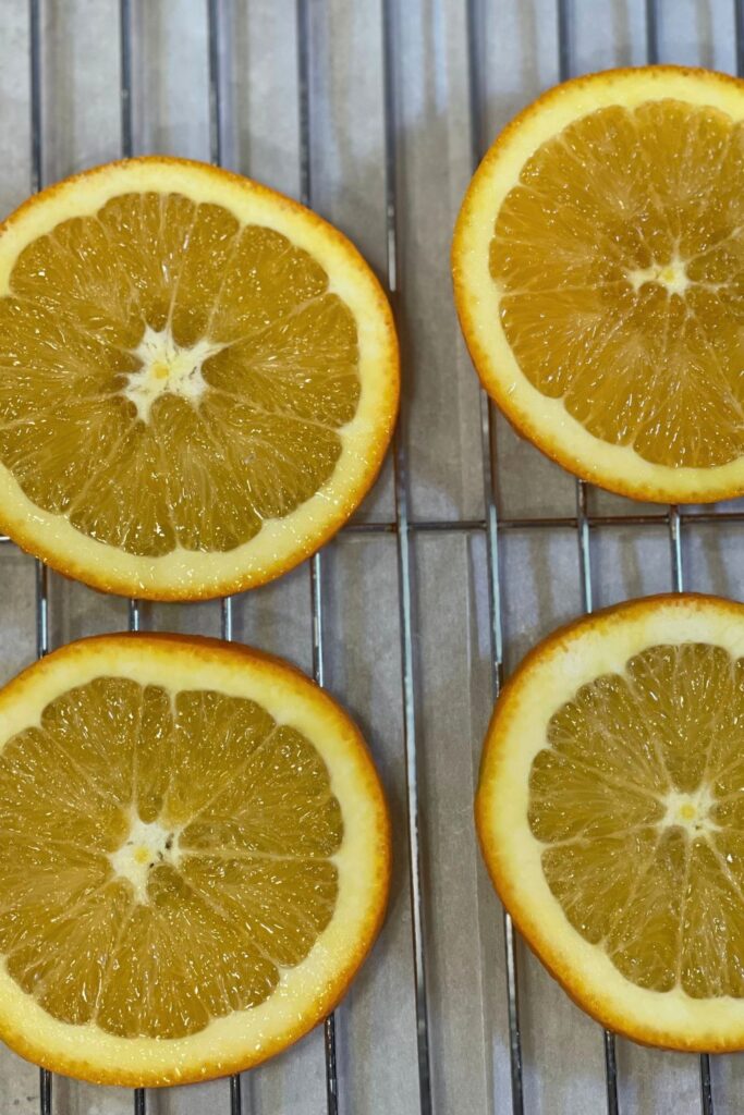 thin orange slices on a metal cooling rack ready to go into the oven to be dried for Christmas decoration