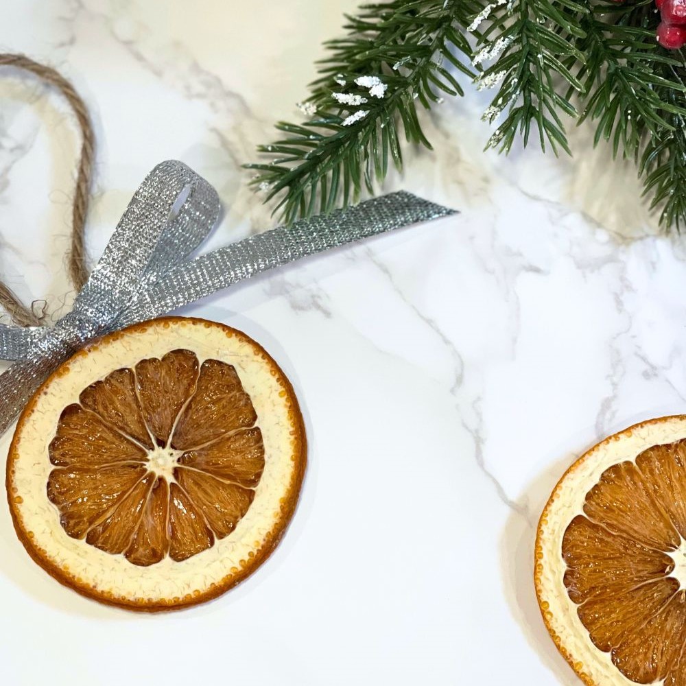 final stage of orange slices dried in the oven, with a ribbon bow and jute hanger to be hung on a Christmas tree