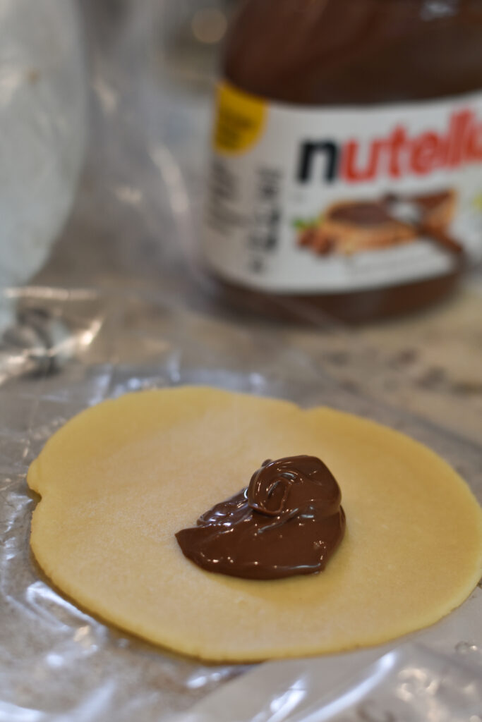 a dollop of Nutella in the center of a disc of sweet empanada dough
