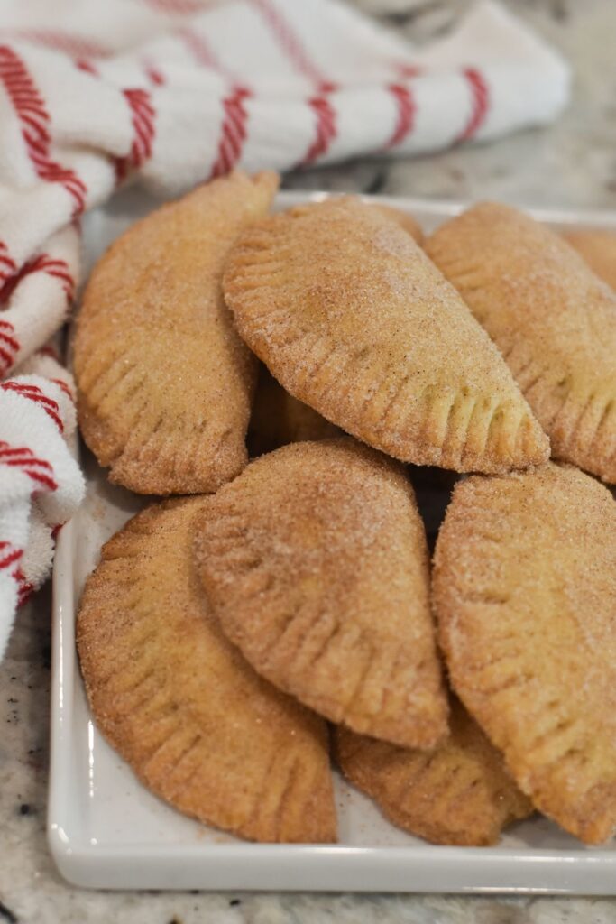 sweet empanadas coated in cinnamon sugar on a plate ready to eat, empanadas dulces